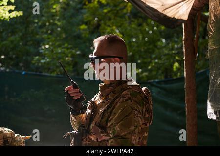 Un maggiore militare utilizza una radio Motorola per comunicare senza problemi con i suoi compagni durante un'operazione tattica, dimostrando professionalità Foto Stock