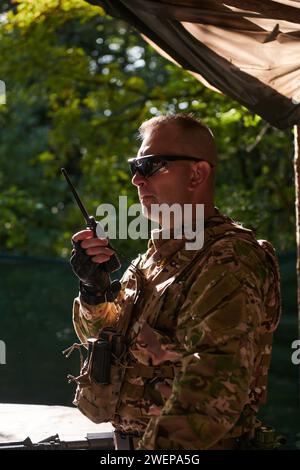 Un maggiore militare utilizza una radio Motorola per comunicare senza problemi con i suoi compagni durante un'operazione tattica, dimostrando professionalità Foto Stock