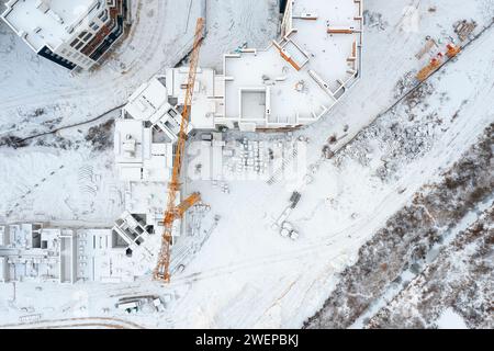 Vista dall'alto di un cantiere con gru coperte di neve. Paesaggio urbano aereo. Foto Stock