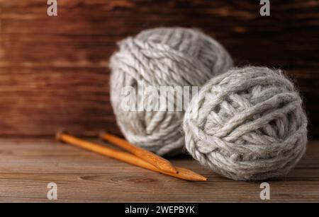 Palle di aghi per maglieria in filato di lana su fondo di legno. Accessori per maglieria. Foto Stock