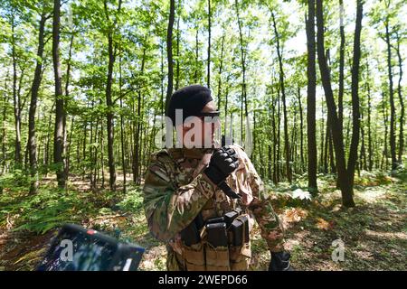 Un maggiore militare utilizza una radio Motorola per comunicare senza problemi con i suoi compagni durante un'operazione tattica, dimostrando professionalità Foto Stock