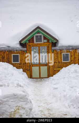 Cottage in legno di inizio '900 ricoperto da uno spesso strato di neve. Foto Stock