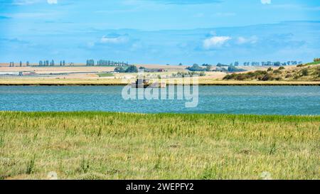 Barca naufragata nell'estuario di Swale a Oare vicino a Faversham - Kent con l'isola di Sheppey in lontananza Foto Stock