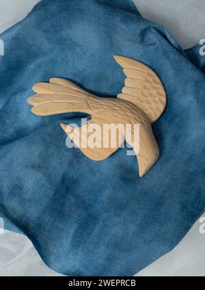 Un grande uccello a forma di colomba scolpito su tessuto blu sembra scendere in volo. Le ali sono allungate come se venissero per la pace e l'amore. Foto Stock