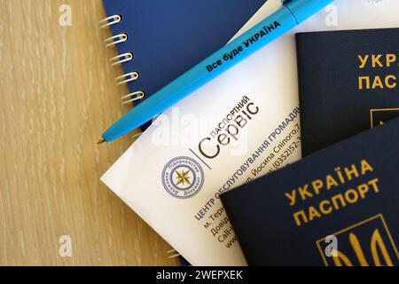 KIEV, UCRAINA - 27 NOVEMBRE 2023 logo del servizio passaporti con passaporto ucraino internazionale e penna sul tavolo Foto Stock