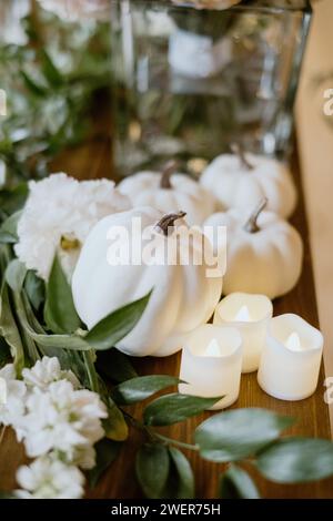 Alcune candele, zucca e fiori su un tavolo come decorazioni autunnali Foto Stock