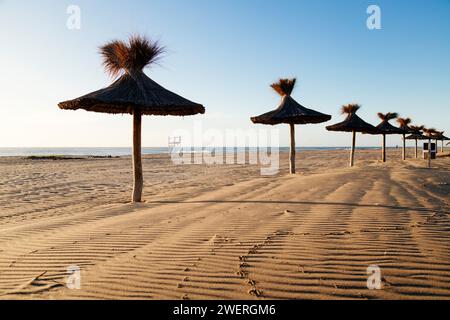Ombrelloni di paglia in prospettiva. Bella mattina d'estate in spiaggia. Mar Azul, Argentina. Foto Stock