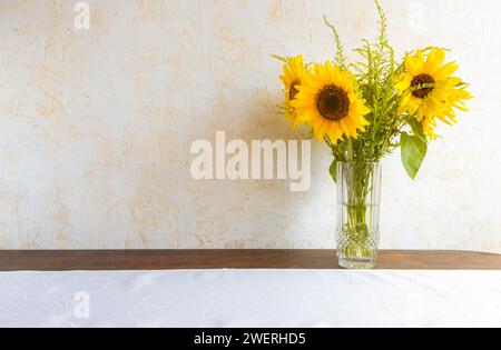 Un bouquet di splendidi girasoli in un vaso di vetro sul tavolo. Design floreale. Foto Stock