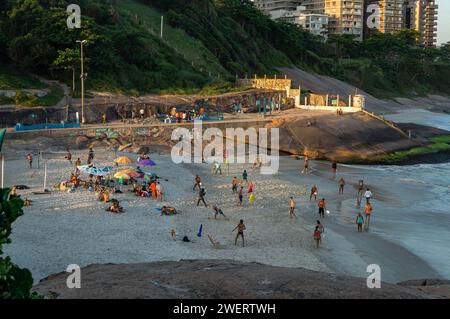 Persone che praticano sport e si godono un po' di tempo sulla piccola spiaggia di Praia do Diabo tra i quartieri di Ipanema e Copacabana durante il pomeriggio estivo. Foto Stock