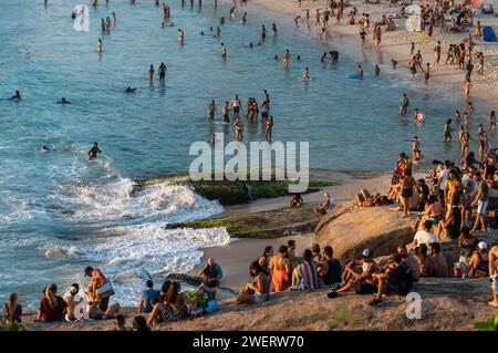 Molti turisti si riuniscono sui dintorni della penisola rocciosa di Arpoador presso la spiaggia di Arpoador per guardare il sole tramontare sulle acque dell'oceano Atlantico. Foto Stock