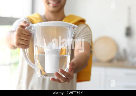 Giovane con caraffa filtro acqua in cucina Foto Stock