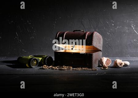 Torace, tesori, conchiglie e binocoli su sfondo scuro Foto Stock