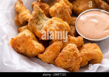 Pepite fritte di pesce gatto in una ciotola con salsa Foto Stock