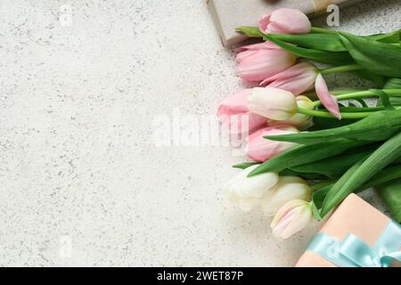 Bouquet di splendidi tulipani e confezioni regalo su sfondo bianco. Giornata internazionale della donna Foto Stock