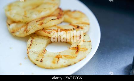 Fette di ananas grigliate su piatto bianco. Barbecue con piatti alla griglia sul retro. Concetto di cibo e cucina. Foto Stock