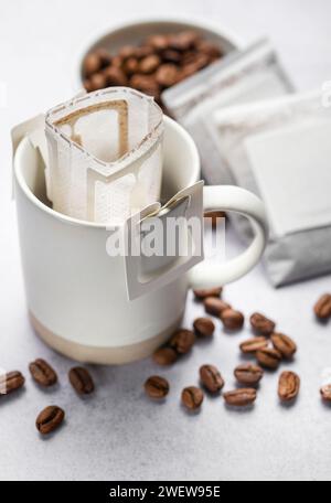 Una tazza di caffè gocciolante appena fatto. Versare il sacchetto del caffè con il caffè macinato per l'erogazione in una tazza Foto Stock