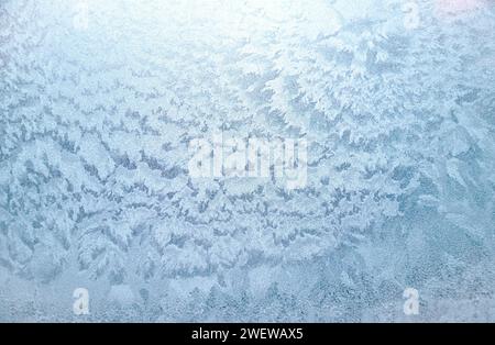 Finestra invernale con superficie congelata, motivo ghiaccio come sfondo o trama. Motivi invernali astratti neve sul vetro Foto Stock