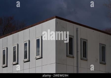 Un edificio in cemento bianco quadrato non descritto con finestre sottili sotto un cielo spiovente. Kanagawa, Giappone. Foto Stock