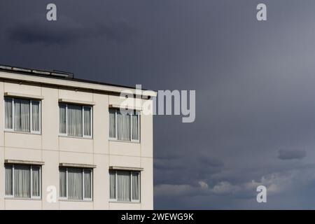 Un edificio in cemento bianco non descritto con finestre sotto un cielo spiovente. Kanagawa, Giappone. Foto Stock