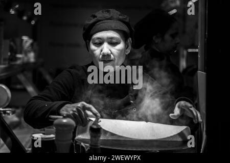 Chef di mezza età che prepara una crepe in un negozio di Street food locale nel quartiere di Montmartre, a Parigi, Francia, Europa Foto Stock