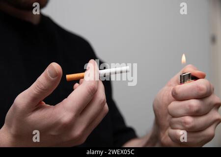 un primo piano di un uomo che inizia a fumare una sigaretta Foto Stock