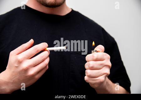 un primo piano di un uomo che inizia a fumare una sigaretta Foto Stock