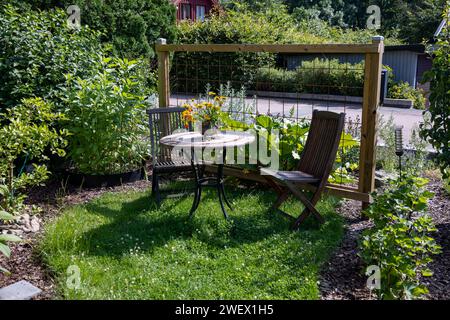 Un'incantevole area salotto esterna con tavolo e sedie in un giardino verde Foto Stock
