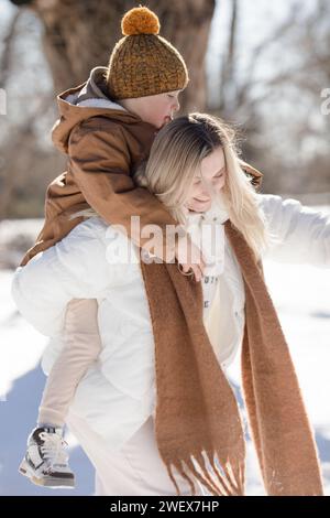 Attività all'aperto per famiglie per buone vacanze invernali. Mamma felice e due figli che giocano a palle di neve su strade innevate in periferia. Buona famiglia in inverno Foto Stock