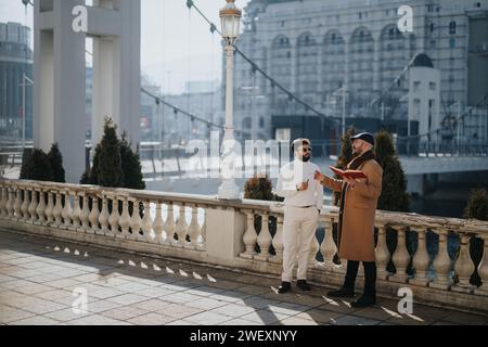 Due uomini eleganti che si impegnano in una vivace conversazione all'aperto in città. Foto Stock