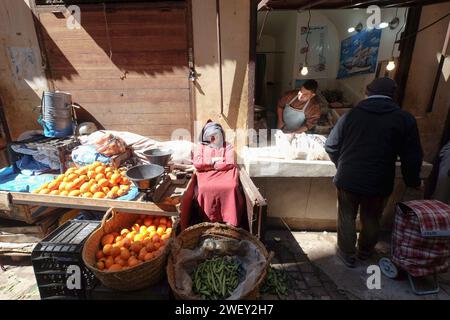Vecchio che vende frutta e verdura nel mercato di fronte alla strada Souk nella città di FES, in Marocco. Negozi locali sulla strada. Foto Stock