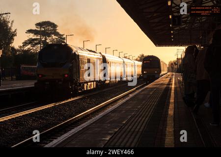 Chiltern Railways classe 68 locomotiva 68013 e classe 168 168002 presso la stazione ferroviaria di Bicester North che cattura il sole nascente con un riflesso dorato Foto Stock