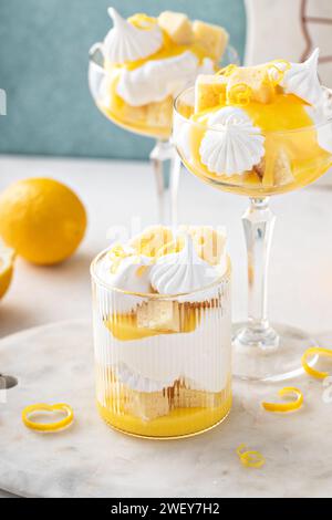 Trifle al limone con torta libbre, cagliata al limone, panna montata e meringa in bicchieri coupé Foto Stock
