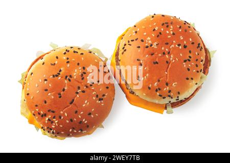 Due hamburger con formaggio, carne ed erbe fresche, cosparsi di semi di sesamo, isolati su uno sfondo bianco. Vista dall'alto Foto Stock