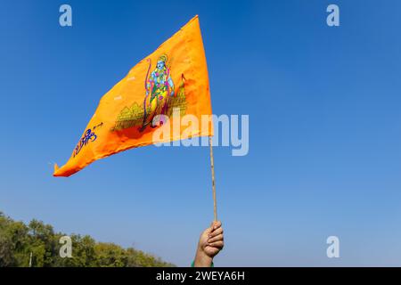bandiera sacra dello zafferano con l'idolo del signore rama in mano con sfondo blu brillante di giorno Foto Stock