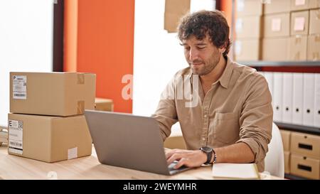 Giovane ispanico, un lavoratore di e-commerce che digita al computer sorridendo in ufficio Foto Stock