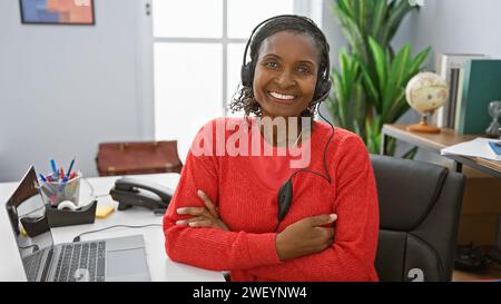 Donna afro-americana sorridente con le cuffie in un moderno ufficio Foto Stock