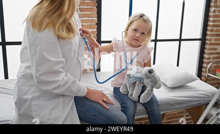 Bambino adorabile giocare-esame con doc utilizzando stetoscopio in clinica, miglior momento in assistenza sanitaria pediatrica Foto Stock