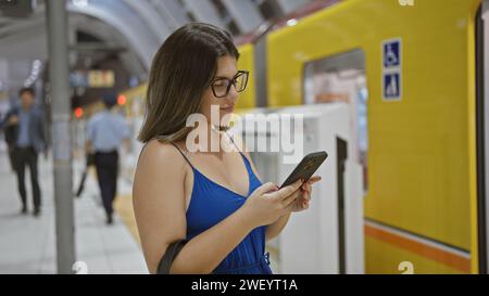 Bellissima donna ispanica con occhiali, al telefono, in attesa del suo viaggio in metropolitana alla stazione di ginza, in mezzo alla vivace vita cittadina Foto Stock