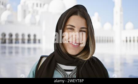 Una giovane donna sorridente che indossa un hijab con uno sfondo moschea sfocato negli emirati arabi uniti. Foto Stock