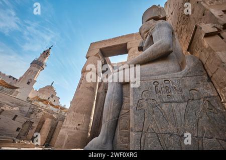 Luxor, Egitto - dicembre 26 2023: Statua di Ramses II e Moschea di Abu Haggagat presso il Tempio di Luxor e. Foto Stock