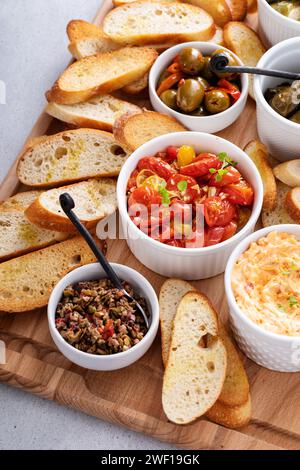 Salse e spuntini con baguette tostate, formaggio pimento, olive e pomodori arrostiti Foto Stock