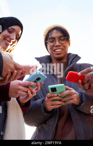 Amici multirazziali in cerchio che usano il telefono all'aperto. Foto Stock