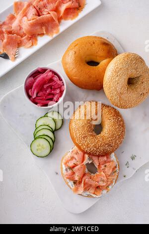 Bagel serviti con formaggio spalmabile, salmone affumicato e cetriolo fresco, bagel con losso di sesamo Foto Stock