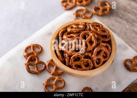 Mini pretzel croccanti con sale in una ciotola di legno, idea di spuntino salato Foto Stock