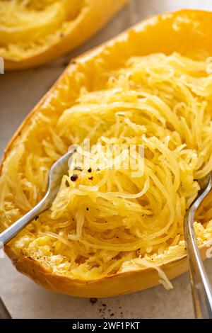 Spaghetti di zucca cotti al forno e tagliati a pezzi con due forchette, pronti da mangiare su una teglia da forno Foto Stock