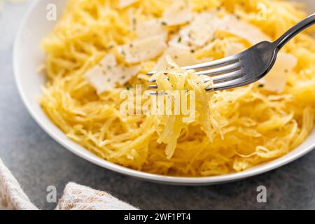 Spaghetti di zucca arrostiti e tagliati a pezzi serviti con olio d'oliva e parmigiano, idea di ricetta a basso contenuto di carboidrati, con una forchetta avvitata Foto Stock