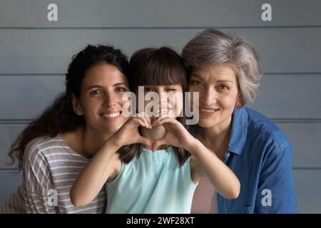 La nonna amorosa e la mamma coccolano la bambina con il segno del cuore Foto Stock