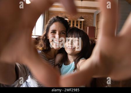 Legare madre e figlio latini fanno il cuore del dito con il selfie Foto Stock