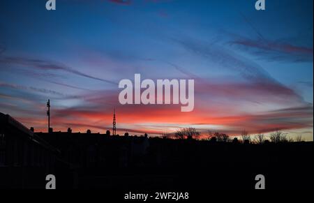 Brighton Regno Unito 28 gennaio 2024 - per la maggior parte della Gran Bretagna oggi si prevede un bel sorgere del sole sopra il trasmettitore Whitehawk ad est di Brighton . Si ritiene che il rossore del cielo sia stato causato dalla polvere del Sahara: Credit Simon Dack / Alamy Live News Foto Stock