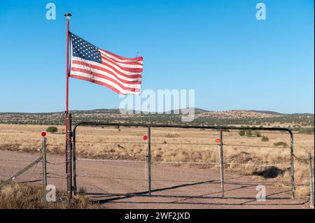 Bandiera americana che sventola con orgoglio su una recinzione contro un paesaggio arenato Foto Stock